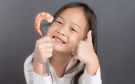 a girl holding a fork and shrimp