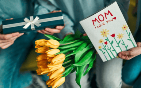 a person holding a bouquet of yellow tulips and a gift box