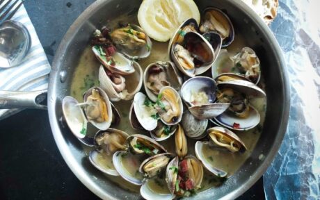 a bowl of clams with a lemon wedge