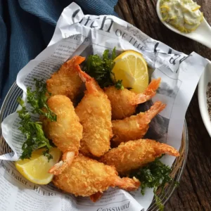 a plate of fried shrimp with lemon slices and greens