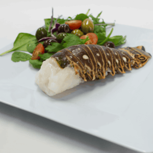 a lobster tail on a plate with salad