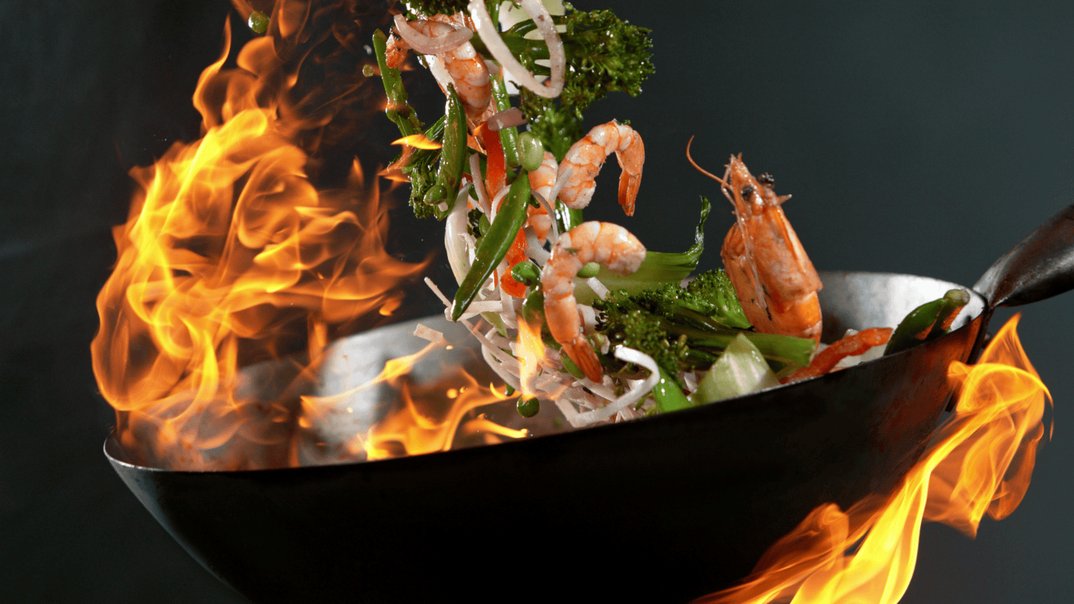 a wok with shrimp and vegetables being cooked
