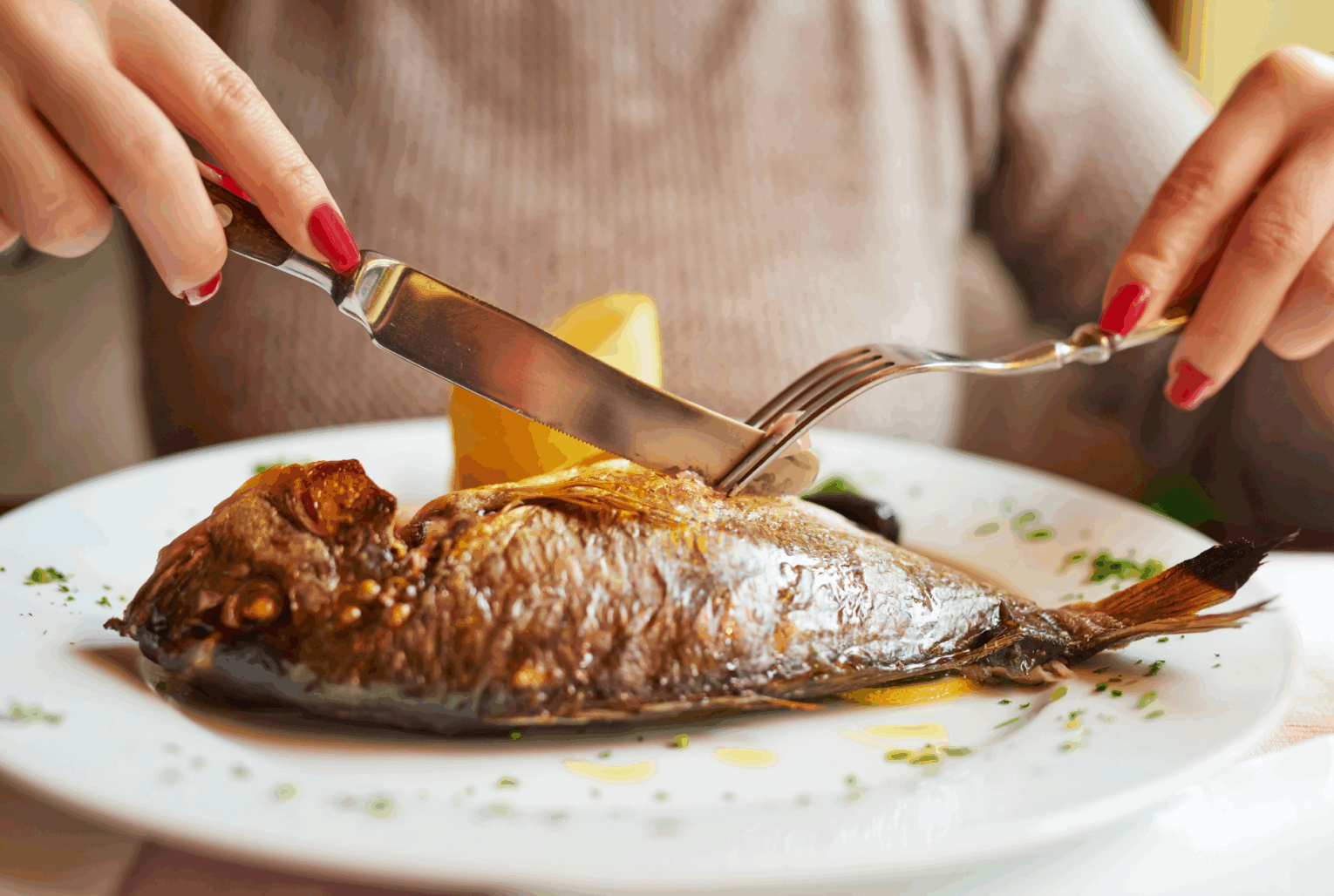 a person cutting a fish on a plate